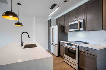 A modern kitchen with a white countertop and dark brown cabinets.